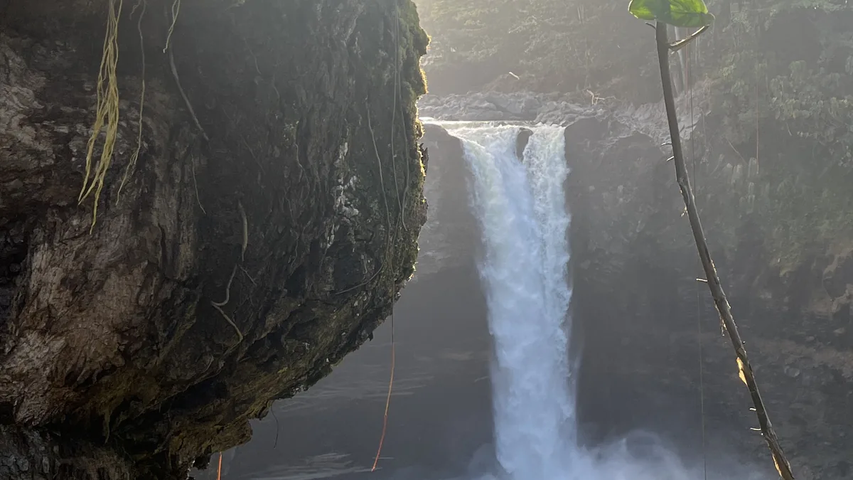 Rainbow Falls dropping into its pool below the shaded cave overlook